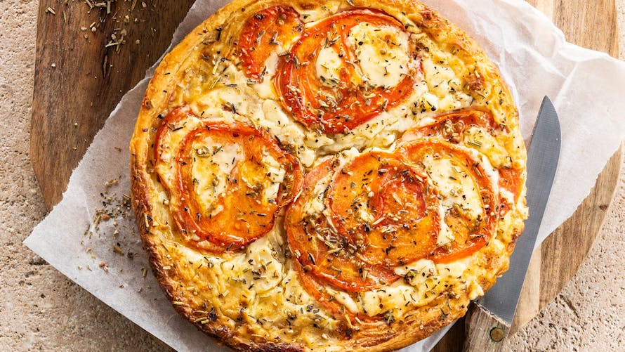 Tarte aux tomates et fromage sur planche en bois.
