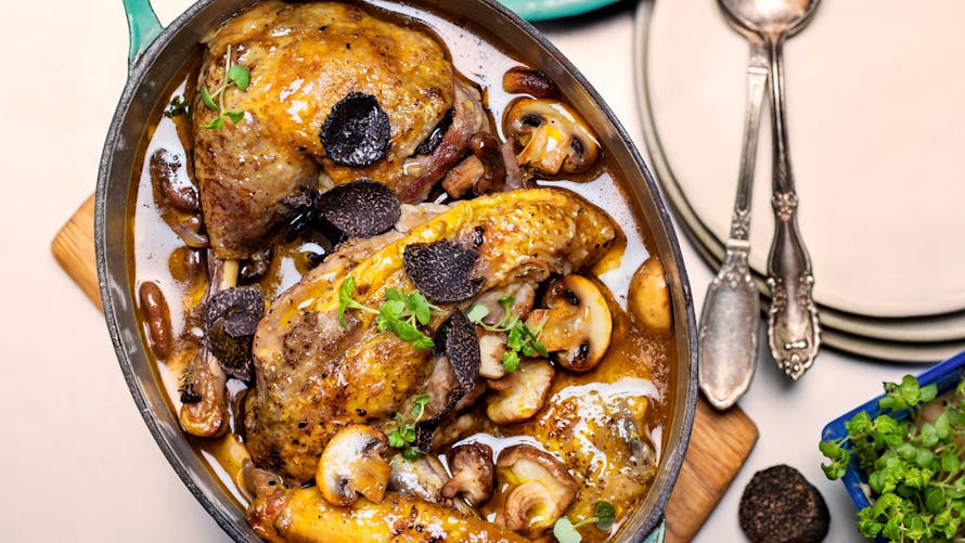 Pintade rôtie aux champignons et herbes dans une cocotte sur une table.
