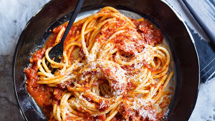 Assiette de spaghetti à la sauce tomate avec du fromage râpé dans une poêle noire.